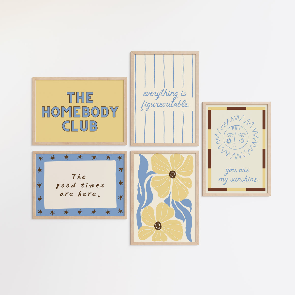Set of five prints in butter yellow and blue: "The Homebody Club," a floral illustration, "everything is figureoutable," "The good times are here" with stars, and "you are my sunshine" with a sun