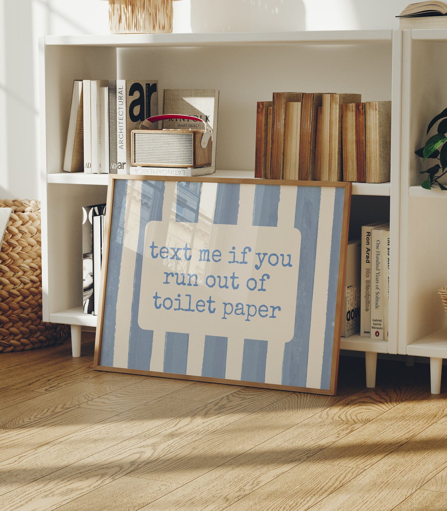Horizontal wall print with dusty blue vertical brush stripes and a cream rounded text box in retro typewriter font reading text me if you run out of toilet paper