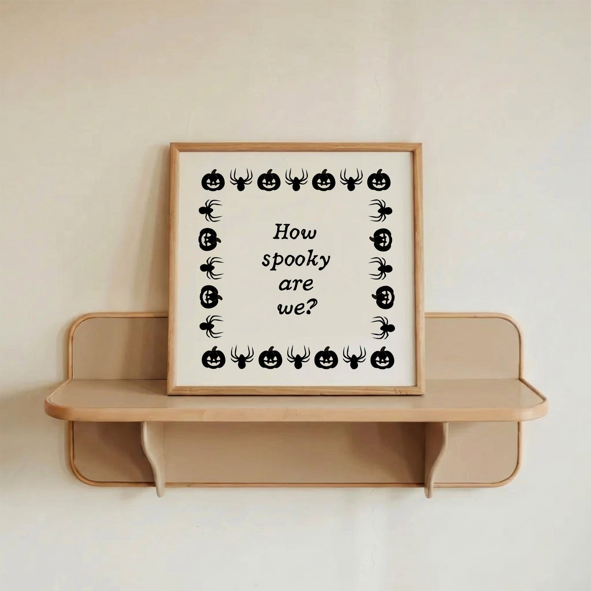 Square digital print with a cream background bordered by alternating black pumpkin and spider illustrations, framing the hand-lettered phrase "How spooky are we?" in black script.