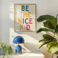 Vertical print with the words "BE THE NICE KID" stacked in large multicolored bubble letters on a cream background in a blue frame.