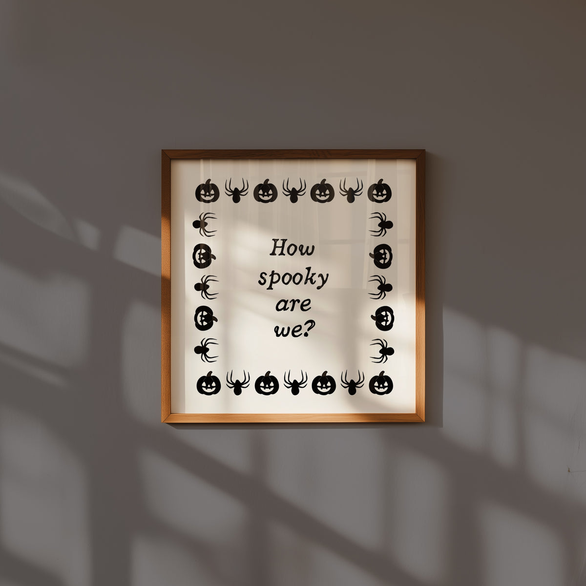 Square digital print with a cream background bordered by alternating black pumpkin and spider illustrations, framing the hand-lettered phrase "How spooky are we?" in black script.