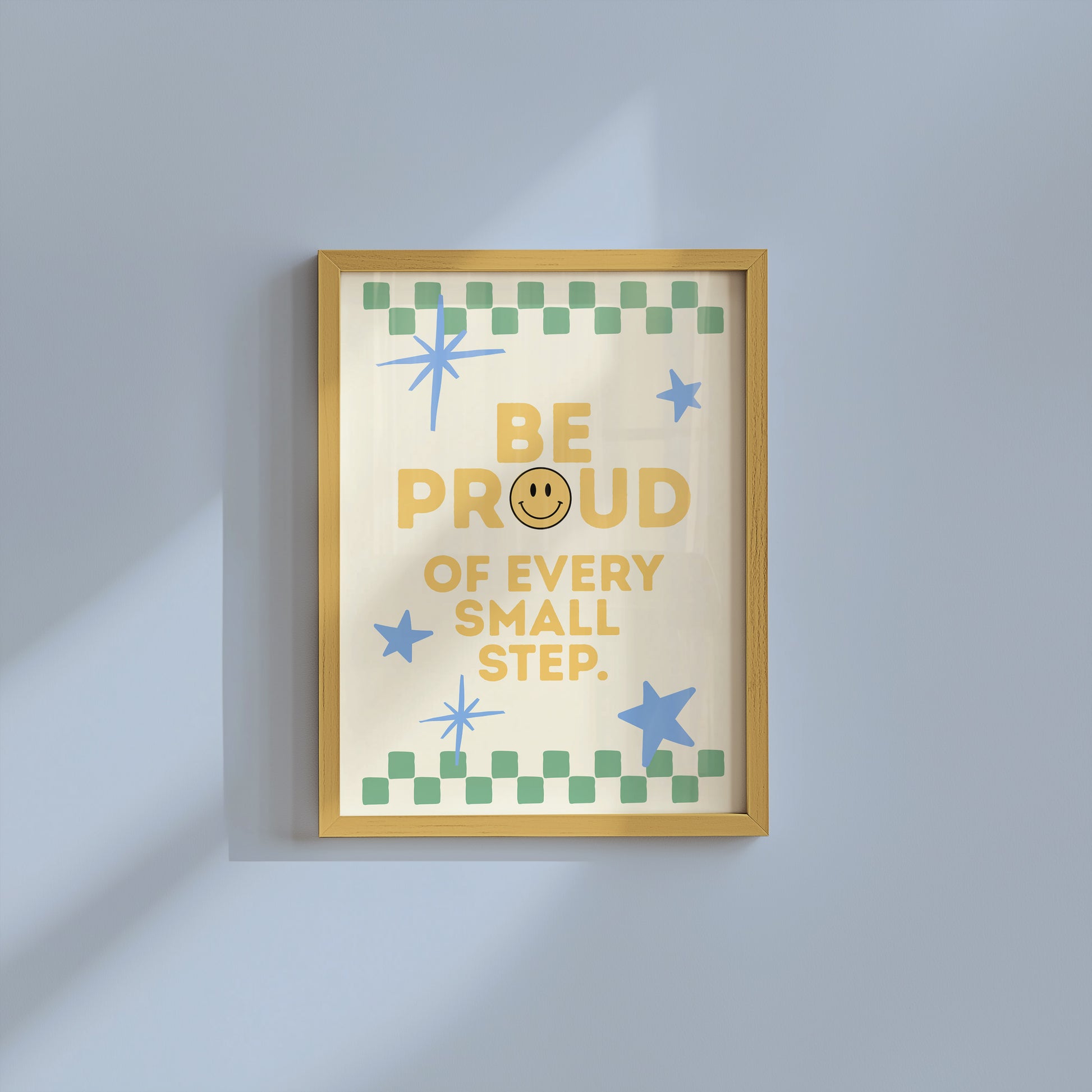 Cream print with a green checkered border, blue stars, and the phrase 'Be Proud of every small step' in yellow lettering with a smiley face replacing the O in Proud