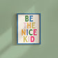 Vertical print with the words "BE THE NICE KID" stacked in large multicolored bubble letters on a cream background in a blue frame.