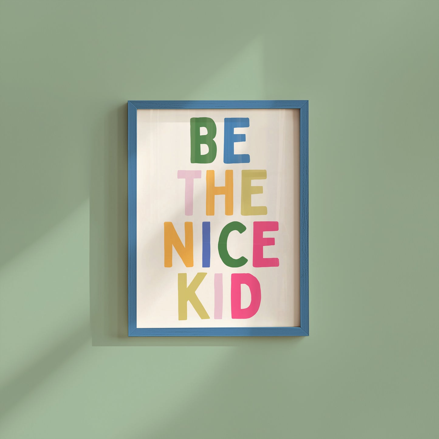 Vertical print with the words "BE THE NICE KID" stacked in large multicolored bubble letters on a cream background in a blue frame.