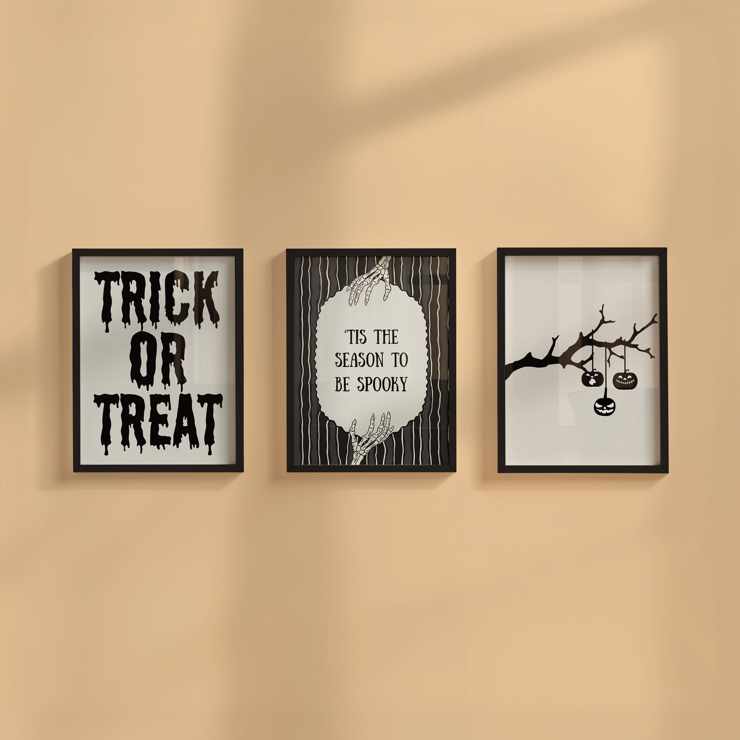 Set of 3 black and white Halloween prints: dripping "Trick or Treat" typography, "'Tis the season to be spooky" framed by skeleton hands, and a black silhouette branch with hanging jack-o'-lanterns.