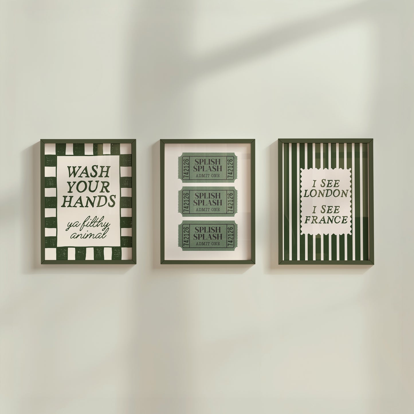 Set of 3 green bathroom prints: "Wash your hands ya filthy animal" in green cursive bordered by a green and cream checkered frame, three green ticket-stub illustrations reading "Splish Splash, Admit One," and "I See London I See France" in a scalloped stamp frame on green and cream stripes.