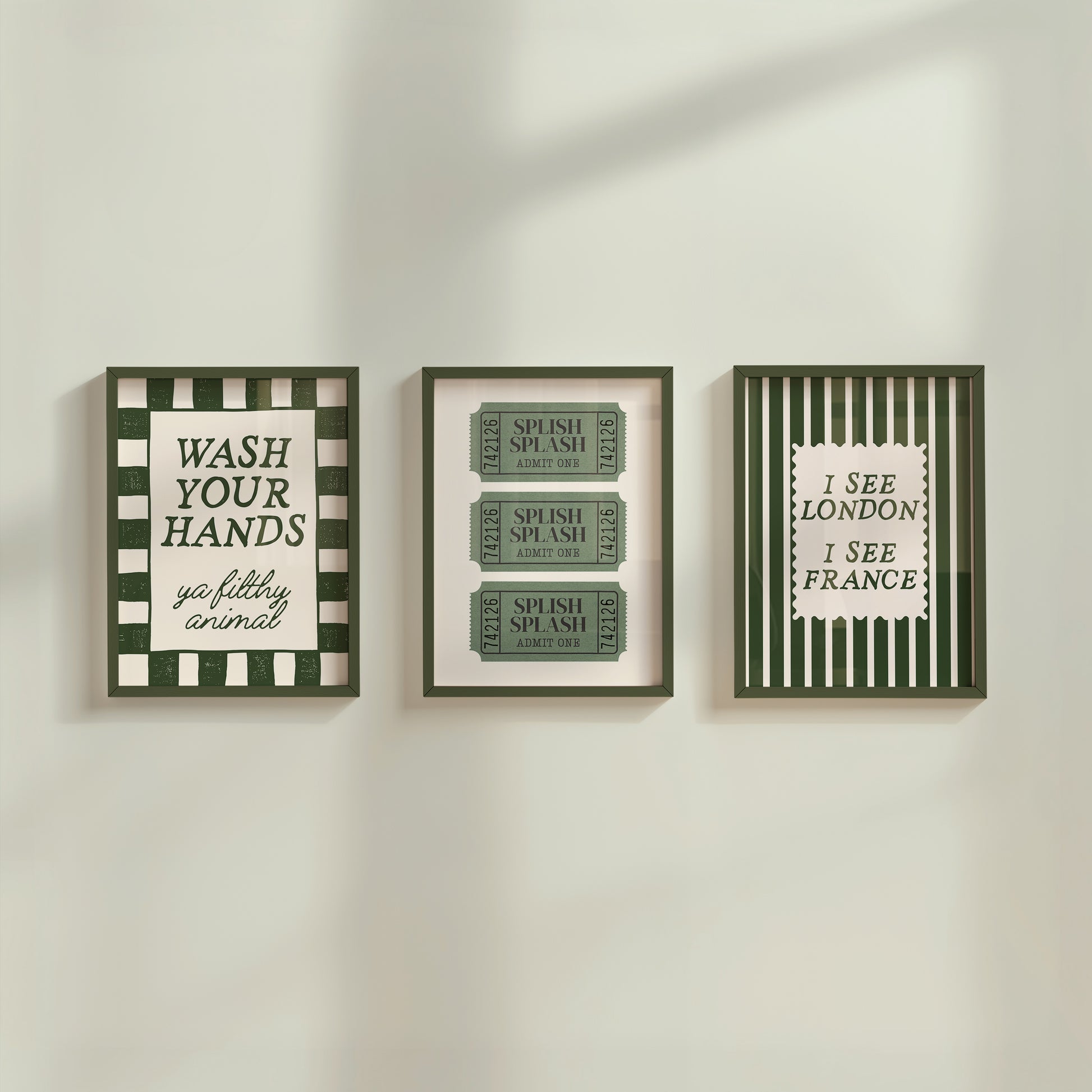 Set of 3 green bathroom prints: "Wash your hands ya filthy animal" in green cursive bordered by a green and cream checkered frame, three green ticket-stub illustrations reading "Splish Splash, Admit One," and "I See London I See France" in a scalloped stamp frame on green and cream stripes.