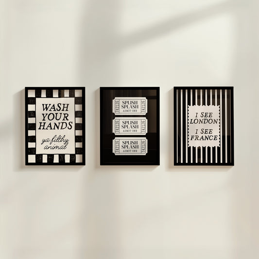 Set of 3 black and white bathroom prints: "Wash your hands ya filthy animal" in black cursive bordered by a black and white checkered frame, three black ticket-stub illustrations reading "Splish Splash, Admit One," and "I See London I See France" in a scalloped stamp frame on black and white stripes.