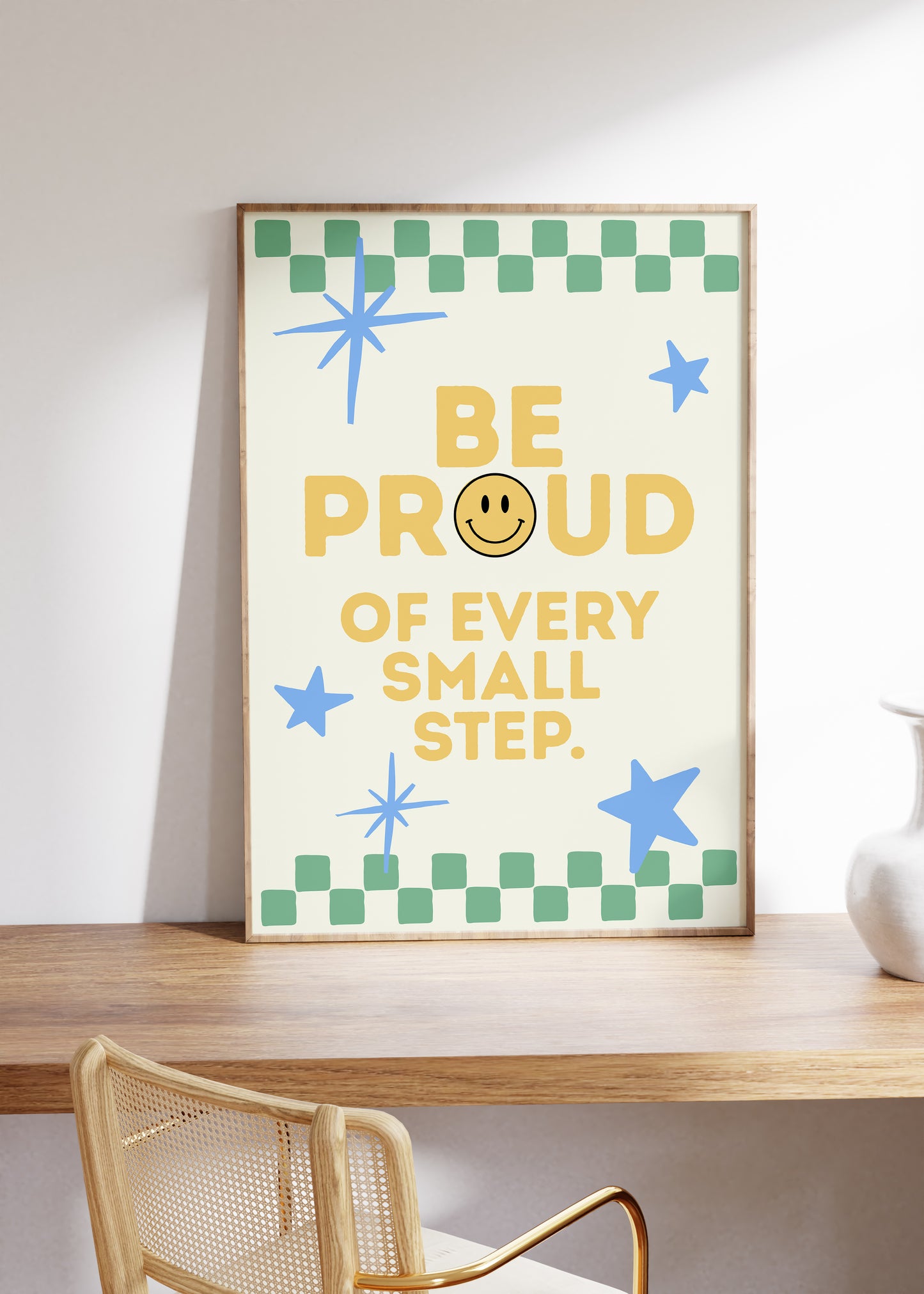 Cream print with a green checkered border, blue stars, and the phrase 'Be Proud of every small step' in yellow lettering with a smiley face replacing the O in Proud