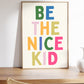 Vertical print with the words "BE THE NICE KID" stacked in large multicolored bubble letters on a cream background in a blue frame.