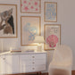 Set of 10 coastal watercolor prints in pink and blue: "Wild Like the Sea" beside a spiral shell illustration, "Stay Wild Ocean Child" in bold blue lettering, "Sea La Vie" in pink stamped typography, a mermaid lounging in a martini glass, pink starfish and seashell illustrations, a woman in a shell headdress, a beach umbrella watercolor, and "Meet me by the sea" in postcard-style script.