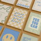 Set of 10 classroom prints in blue, green, and yellow: Yes You Can, Every Voice Matters Here, Slow Down You're Doing Fine, Progress Over Perfection, a starburst Welcome illustration, an Attendance Check print reading Show Up As You Are, Great Minds Grow Here on a checkered background, a smiley face reading Be the Kind Kid, Mistakes Help Us Learn, and Great Things Come to Those Who Try.