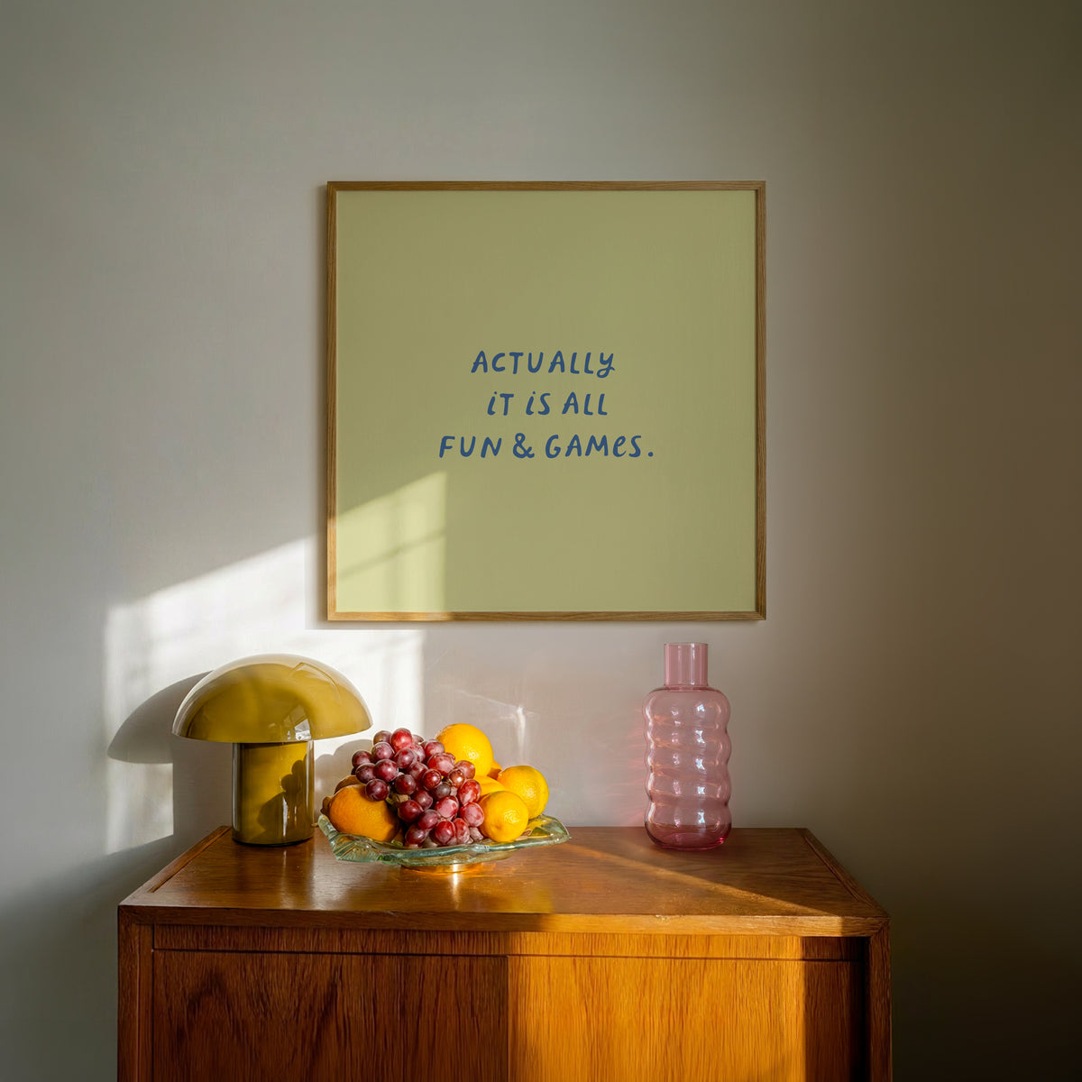 Square print with an olive green background and the quote "Actually it is all fun & games." in bold blue hand-lettered type.