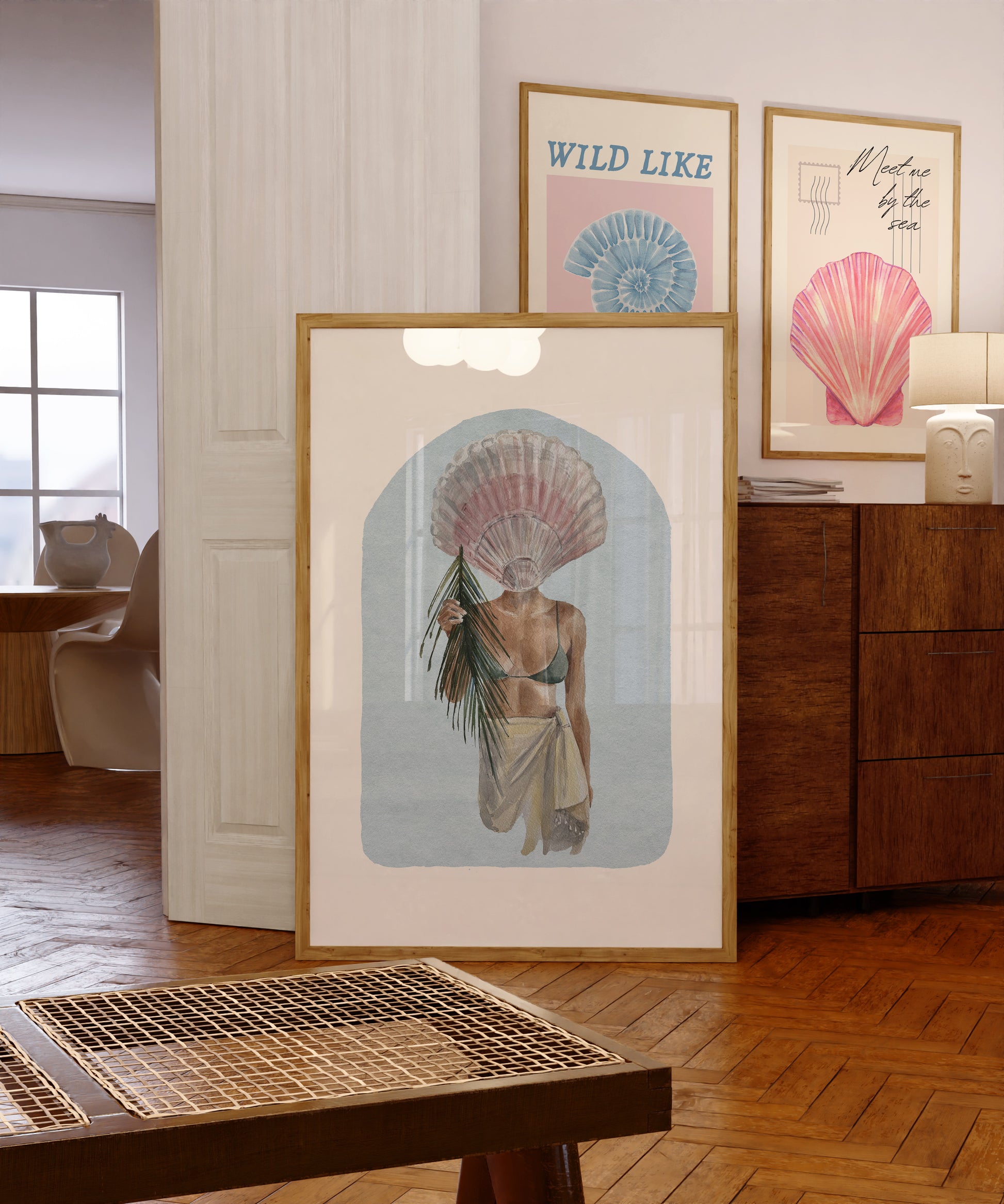 Set of 10 coastal watercolor prints in pink and blue: "Wild Like the Sea" beside a spiral shell illustration, "Stay Wild Ocean Child" in bold blue lettering, "Sea La Vie" in pink stamped typography, a mermaid lounging in a martini glass, pink starfish and seashell illustrations, a woman in a shell headdress, a beach umbrella watercolor, and "Meet me by the sea" in postcard-style script.