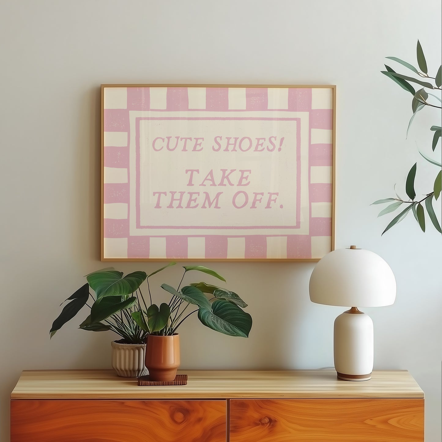Horizontal wall print with pink and cream checkered border and a cream centre text box in bold serif typography reading Cute Shoes! Take Them Off. in dusty pink