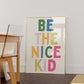 Vertical print with the words "BE THE NICE KID" stacked in large multicolored bubble letters on a cream background in a blue frame.