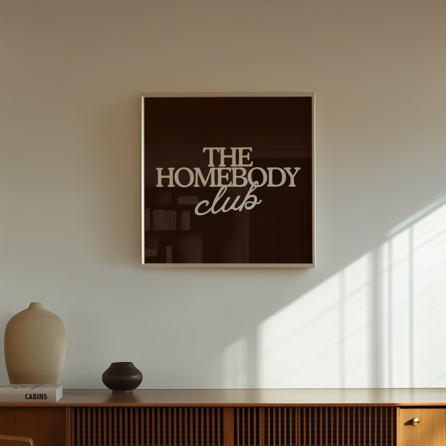 Dark brown print with "The Homebody Club" in bold cream serif and script typography