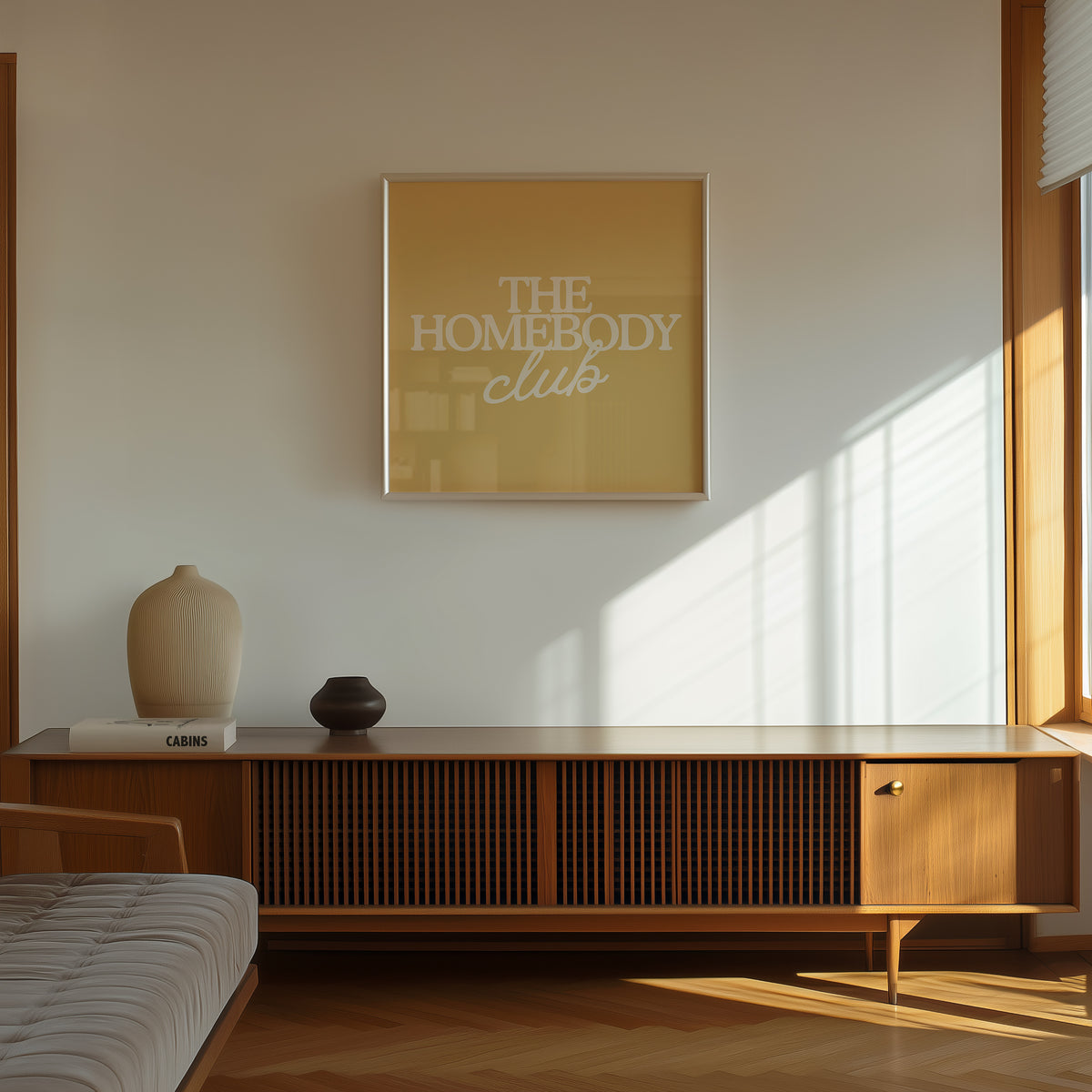 Square digital print with a mustard yellow background featuring "THE HOMEBODY" in bold cream serif type stacked above "club" in cream cursive script, centered typography layout.