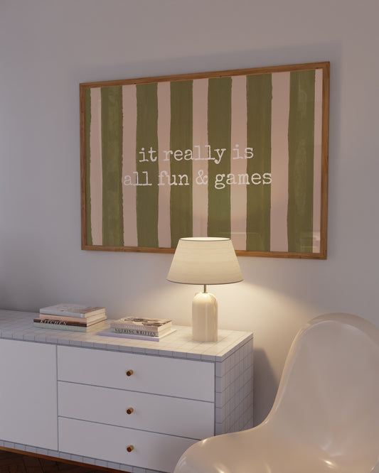 Horizontal print with olive green and cream hand-painted vertical stripes and the quote "it really is all fun & games" in white typewriter-style lettering across the center.