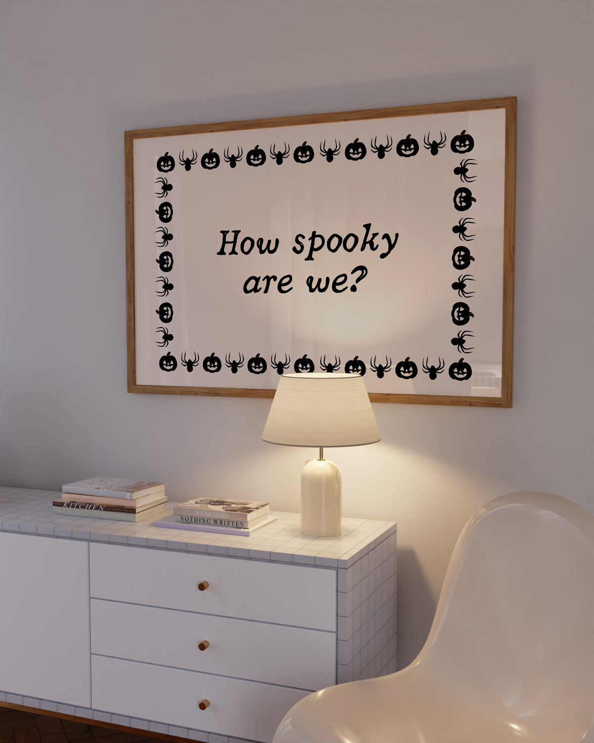 Landscape digital print with a cream background bordered by alternating black pumpkin and spider illustrations, framing the hand-lettered phrase "How spooky are we?" in black script.