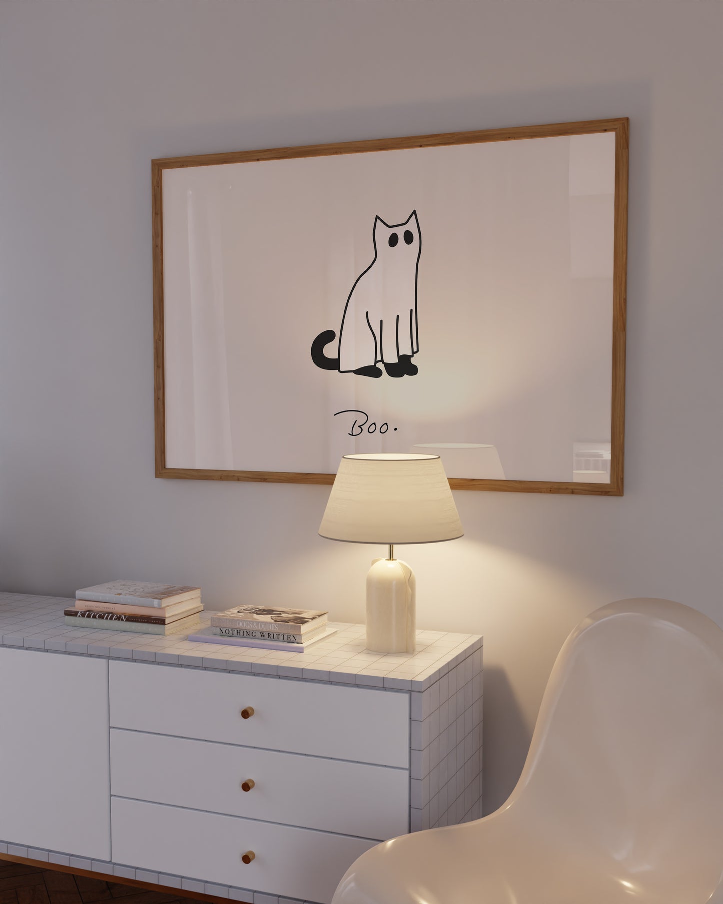 Horizontal minimalist print of a black cat wearing a white ghost sheet costume with cut-out eyes, sitting beside the handwritten word "Boo." on a cream background.