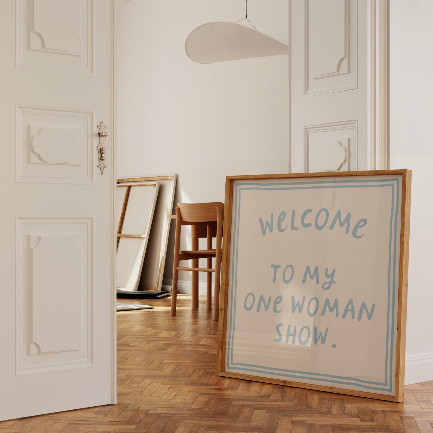 Beige print with dusty blue hand-lettered text "Welcome to my one woman show." inside a double-line border