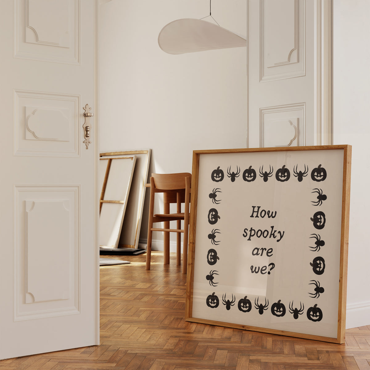 Square digital print with a cream background bordered by alternating black pumpkin and spider illustrations, framing the hand-lettered phrase "How spooky are we?" in black script.