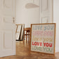 Square print with the words "Love You" repeated five times in different colors, fonts, and styles — blue, pink, gold, red, and green — stacked on a cream background.