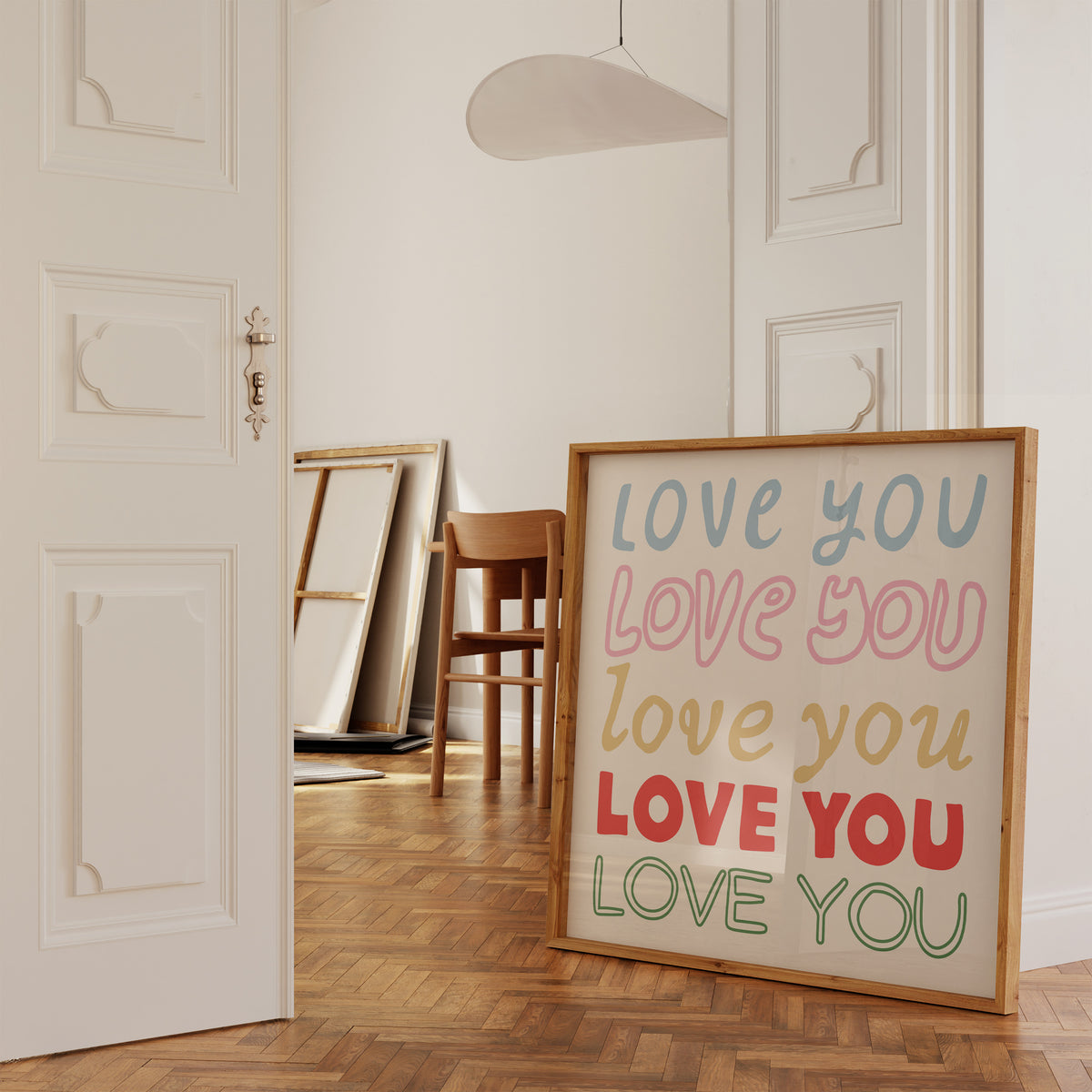 Square print with the words "Love You" repeated five times in different colors, fonts, and styles — blue, pink, gold, red, and green — stacked on a cream background.