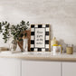 Black and white checkered print with a scalloped border and the handwritten quote "Kisses if you do the dishes" in black script