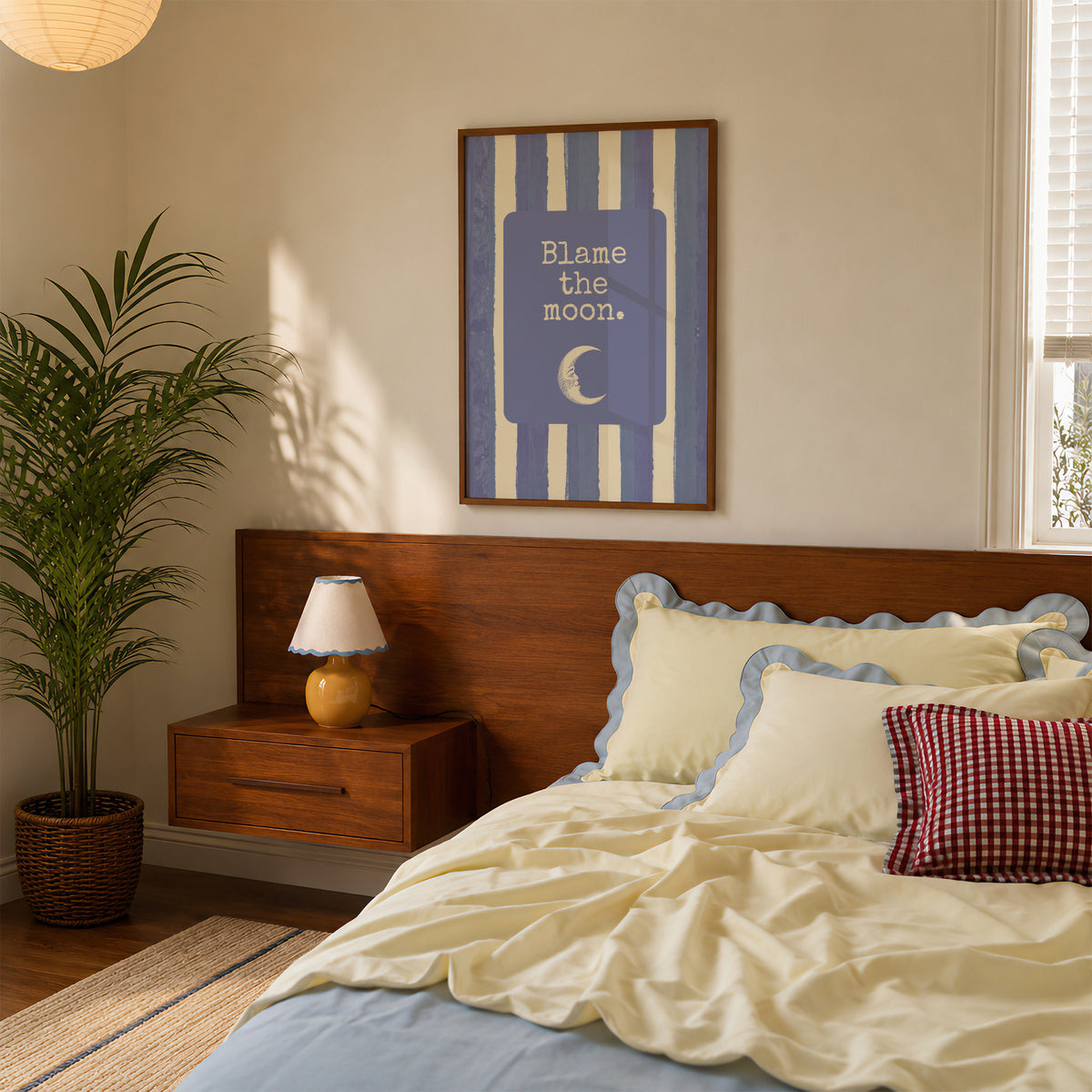 Portrait digital print with blue-and-cream striped background featuring a rounded blue panel with the text "Blame the moon." in cream lettering above a vintage-style crescent moon face illustration.