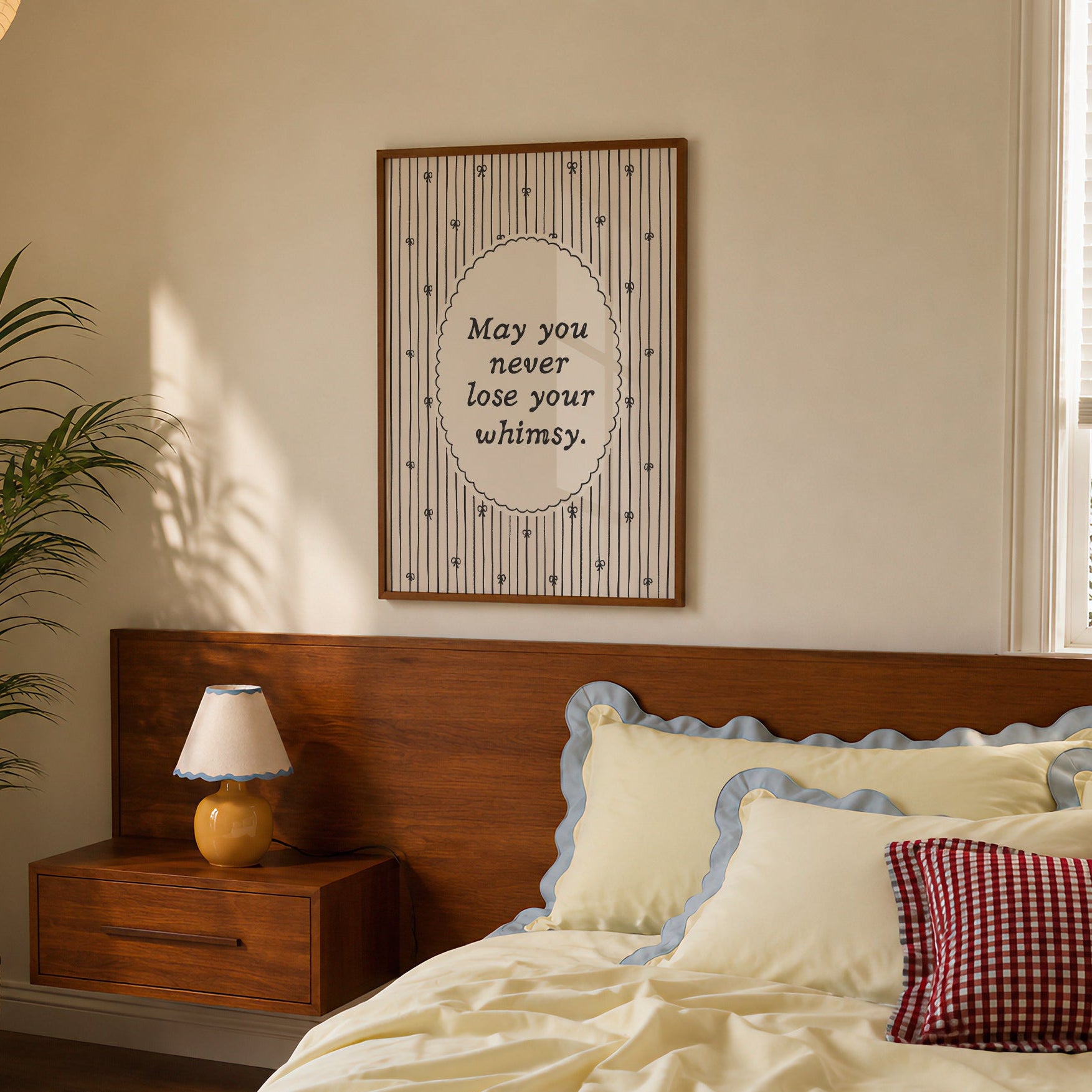 Vertical print with the quote "May you never lose your whimsy." in italic serif type inside a scalloped oval frame, surrounded by thin navy pinstripes decorated with small hand-drawn bows on a cream background.