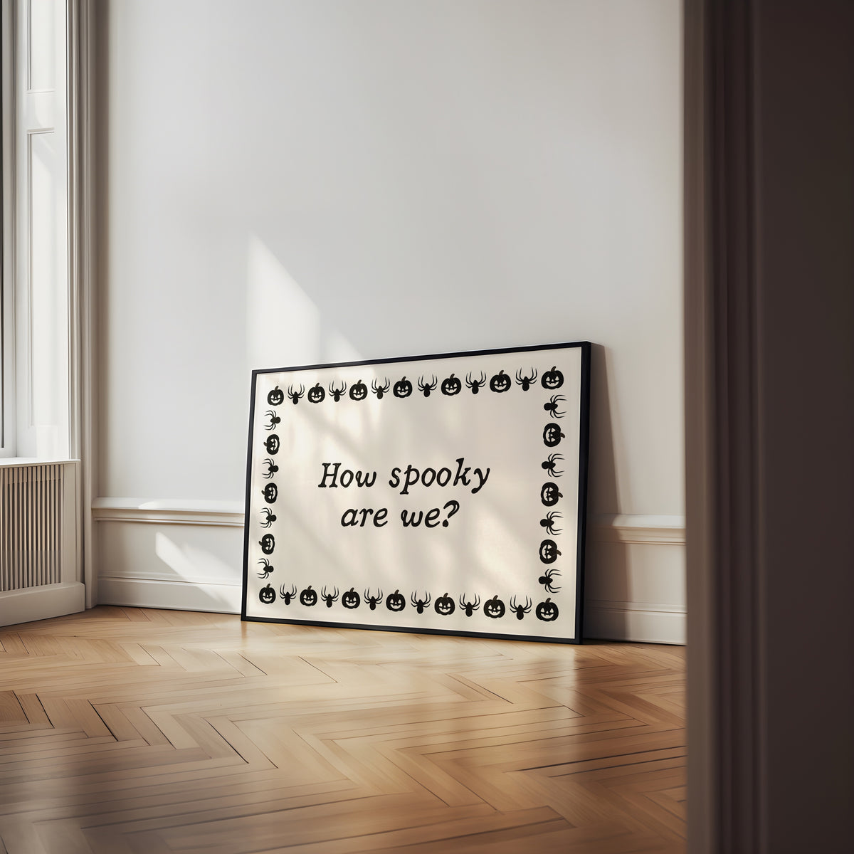 Landscape digital print with a cream background bordered by alternating black pumpkin and spider illustrations, framing the hand-lettered phrase "How spooky are we?" in black script.