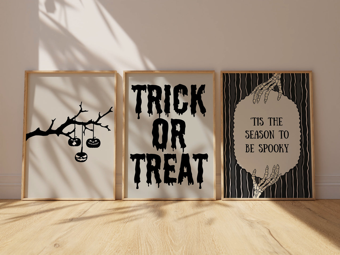 Set of 3 black and white Halloween prints: dripping "Trick or Treat" typography, "'Tis the season to be spooky" framed by skeleton hands, and a black silhouette branch with hanging jack-o'-lanterns.