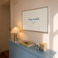 Horizontal print with thin hand-painted tan and cream vertical stripes, the quote "stay awhile" in navy cursive script, and a small hand-drawn smiley face beneath it.