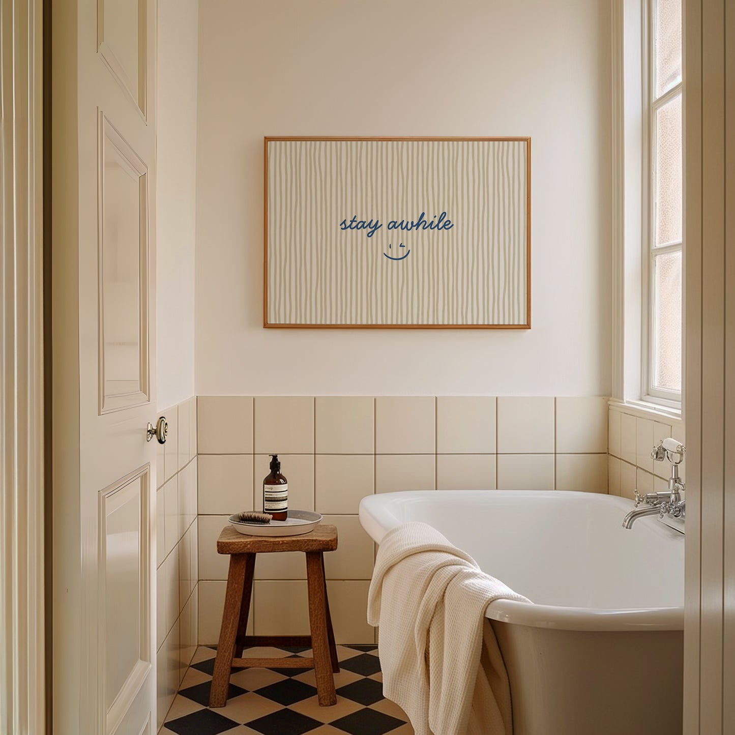 Horizontal print with thin hand-painted tan and cream vertical stripes, the quote "stay awhile" in navy cursive script, and a small hand-drawn smiley face beneath it.