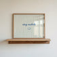 Horizontal print with thin hand-painted tan and cream vertical stripes, the quote "stay awhile" in navy cursive script, and a small hand-drawn smiley face beneath it.