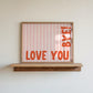 Horizontal wall print with soft pink wavy vertical stripes and bold red rounded typography reading LOVE YOU BYE! in the bottom corner