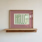Hello retro stripe print in a wood frame on a shelf