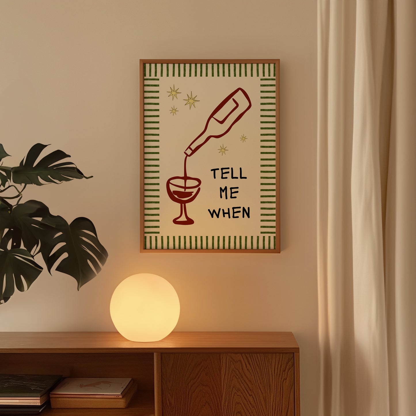 Vertical cream wall print with green stripe border, gold star details, and bold black typography reading Tell Me When alongside dark red hand-drawn line art of a wine bottle pouring into a glass