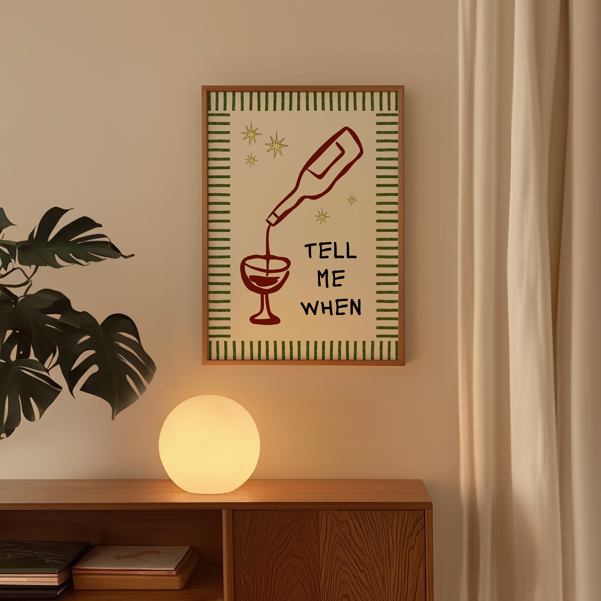 Vertical cream wall print with green stripe border, gold star details, and bold black typography reading Tell Me When alongside dark red hand-drawn line art of a wine bottle pouring into a glass