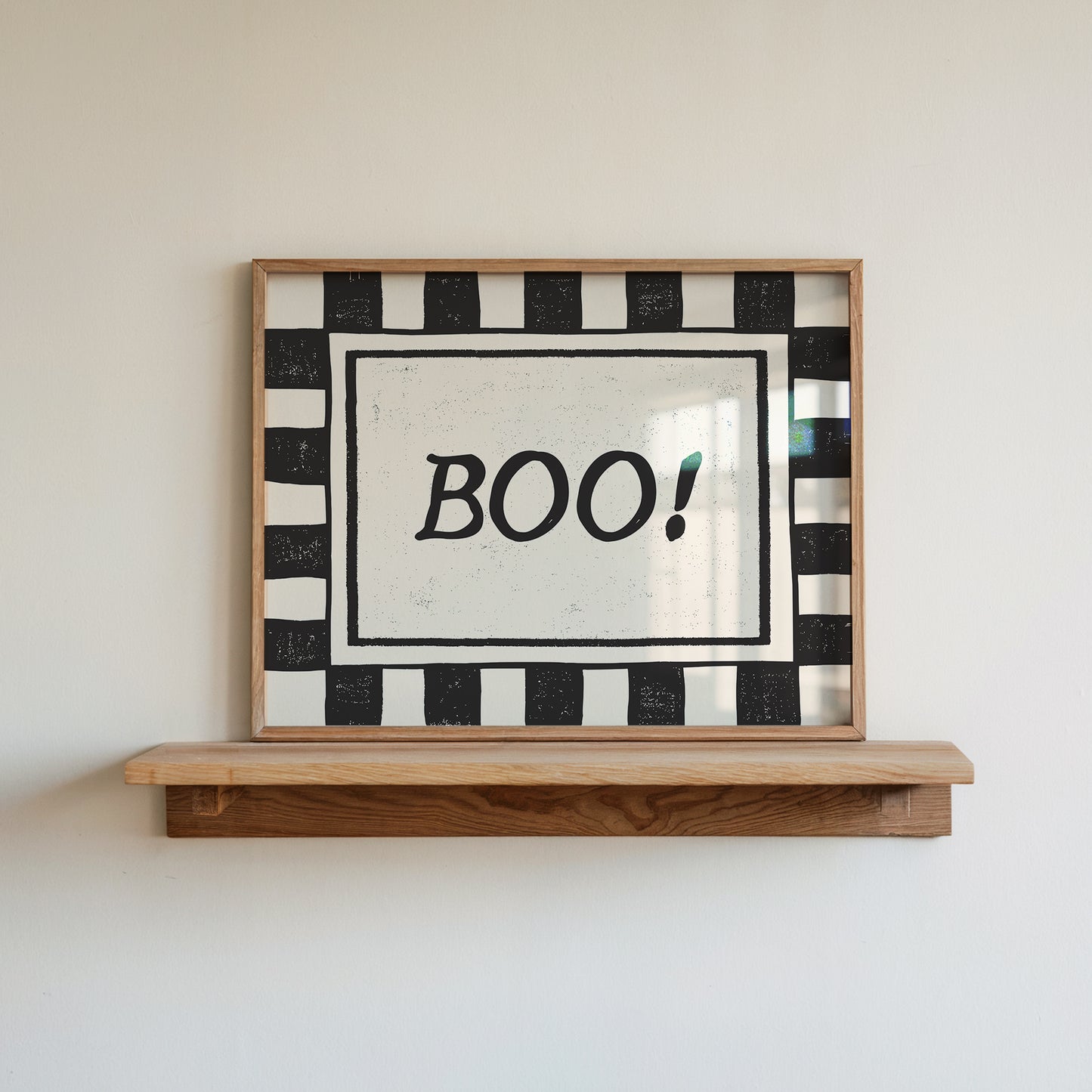 Horizontal print with a bold black and white checkered border framing the word "BOO!" in black hand-drawn type on a textured cream background.