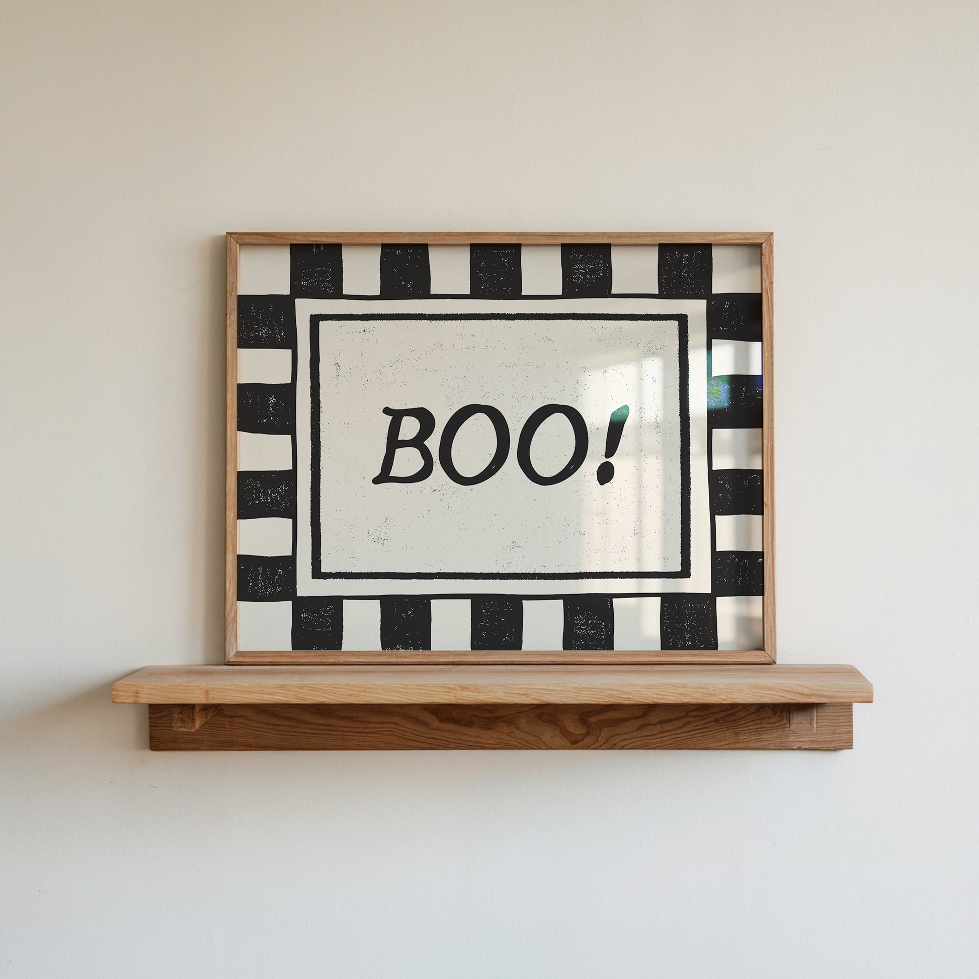 Horizontal print with a bold black and white checkered border framing the word "BOO!" in black hand-drawn type on a textured cream background.