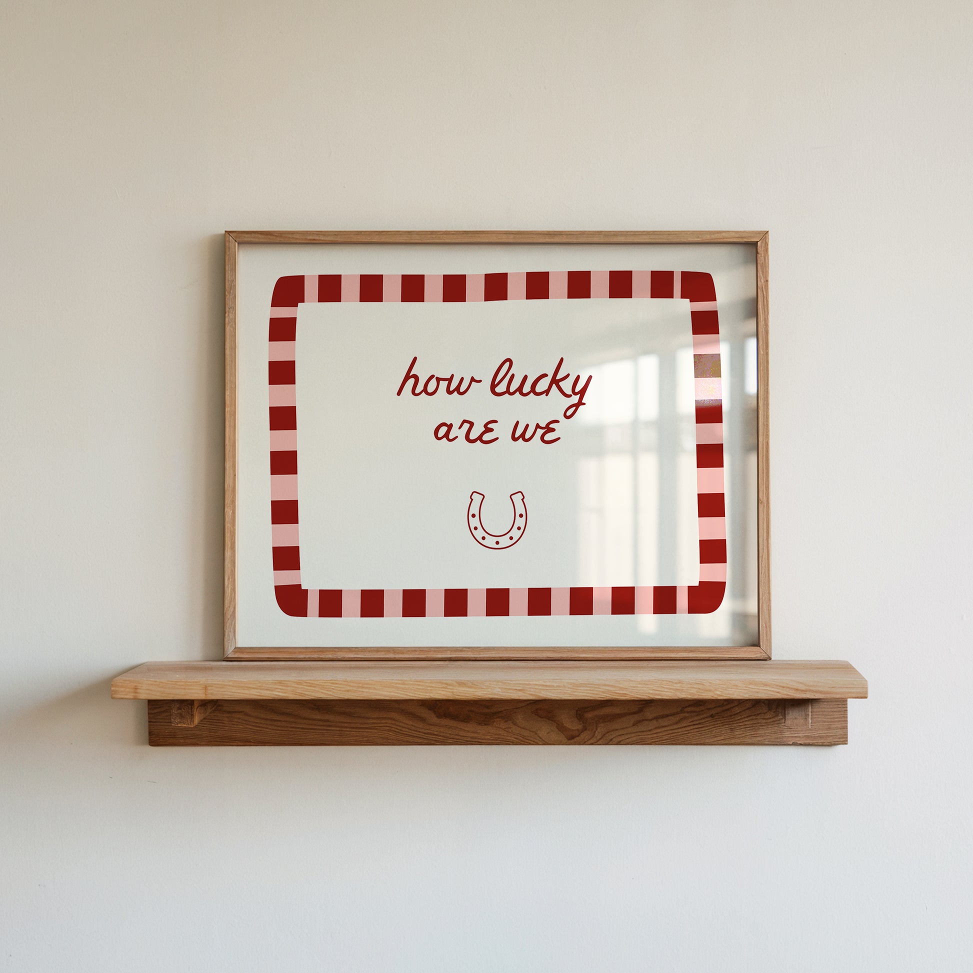 White print with a red and pink striped border featuring the handwritten quote 'how lucky are we' and a horseshoe illustration