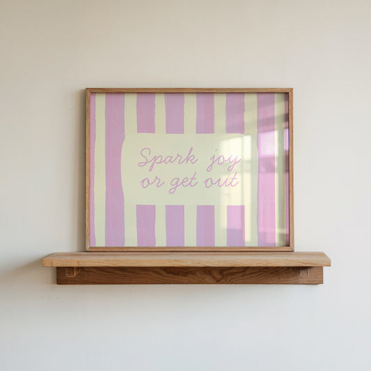 Horizontal art print with hand-painted pink and cream vertical stripes and the quote "Spark joy or get out" in pink cursive script inside a rounded cream panel at the centre.