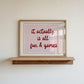 Horizontal wall print with a soft pink centre panel and white border with dark red scalloped outline, bold dark red cursive script reading it actually is all fun & games