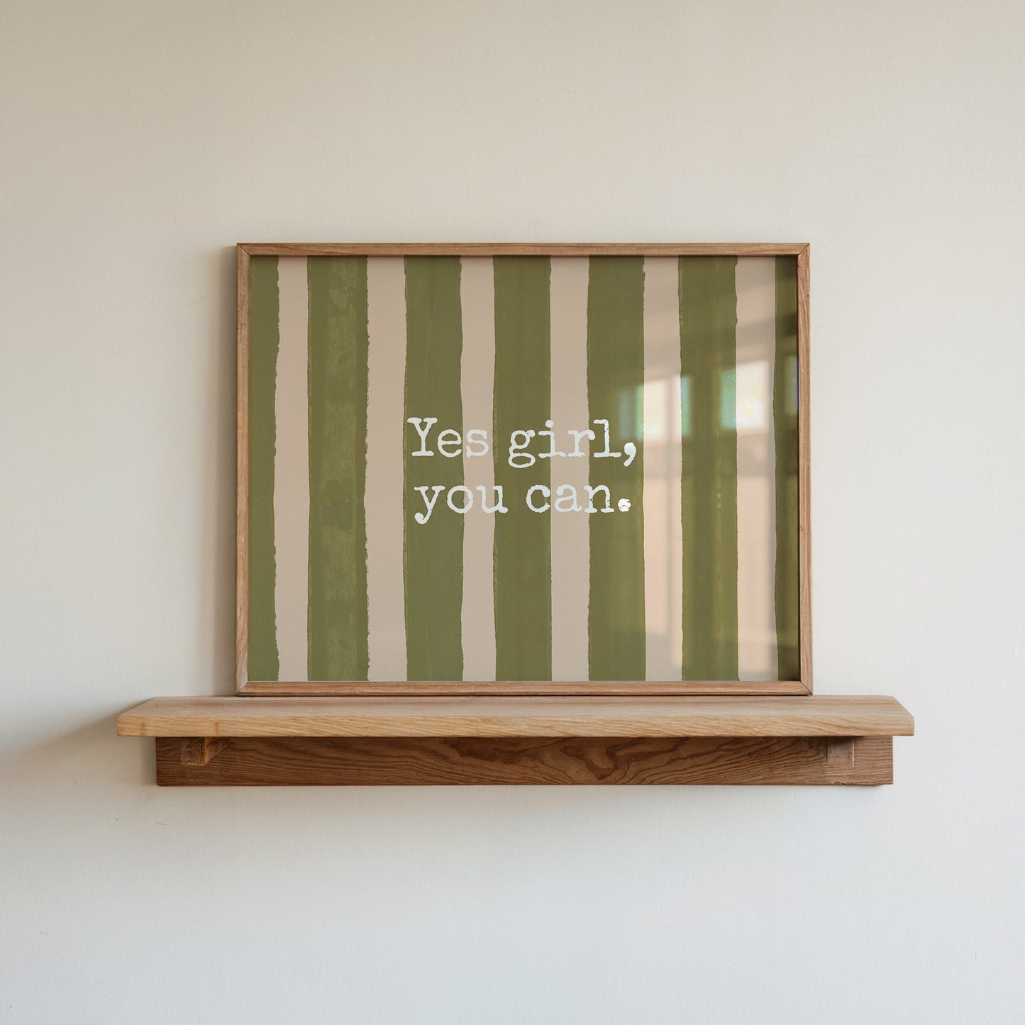 Horizontal wall print with bold olive green brush stroke vertical stripes on a warm cream background with white typewriter font text reading Yes girl, you can.