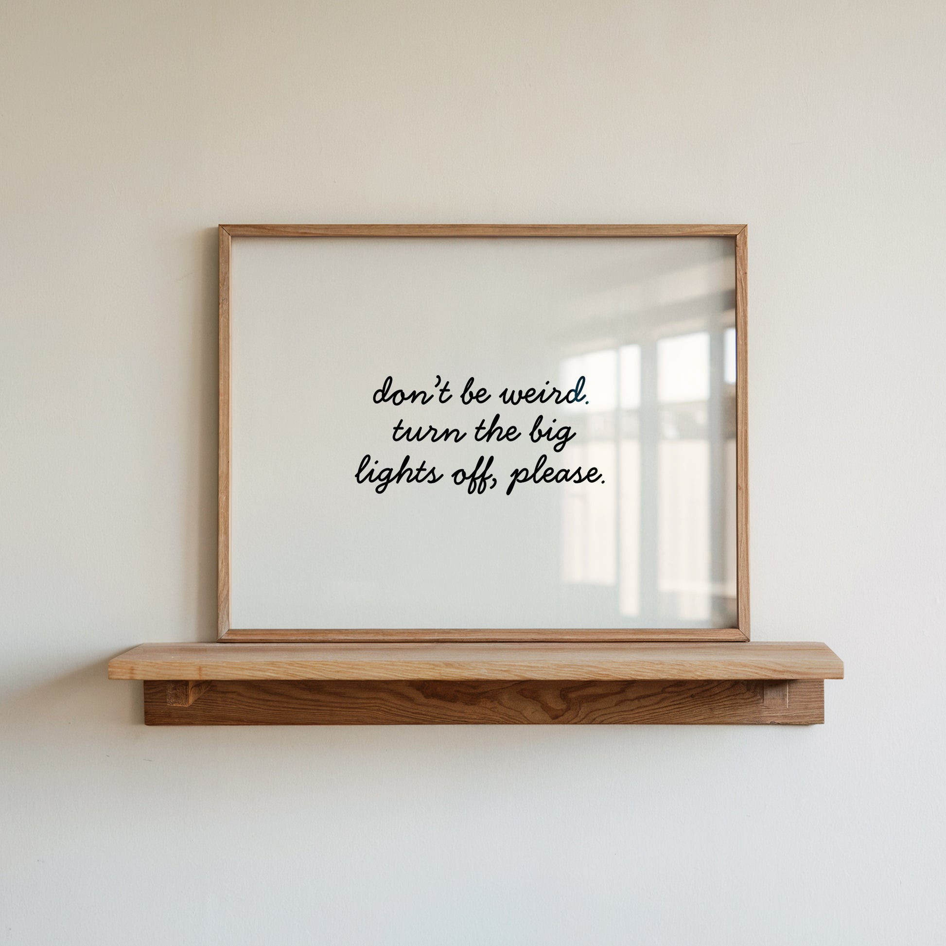 Horizontal white wall print with elegant black cursive script reading don't be weird. turn the big lights off, please.