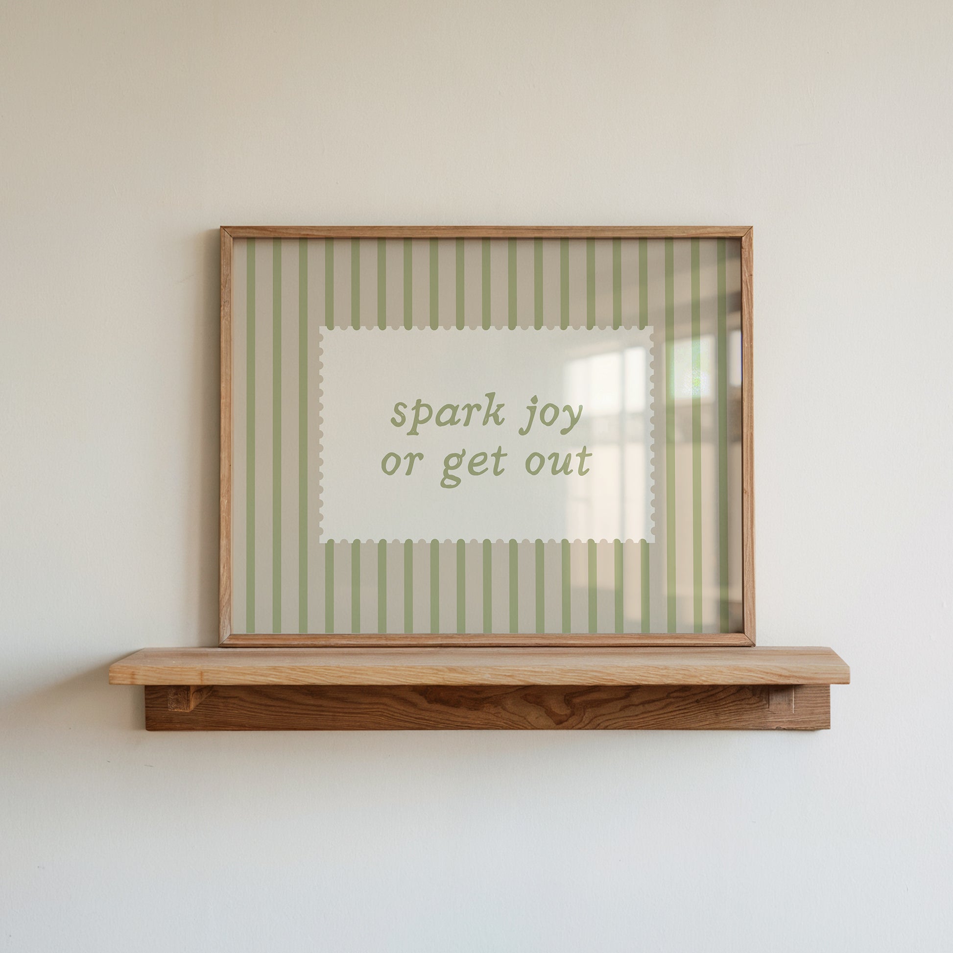 Horizontal wall print with soft sage green vertical stripes and a cream scalloped border text box reading spark joy or get out in matching sage green cursive font