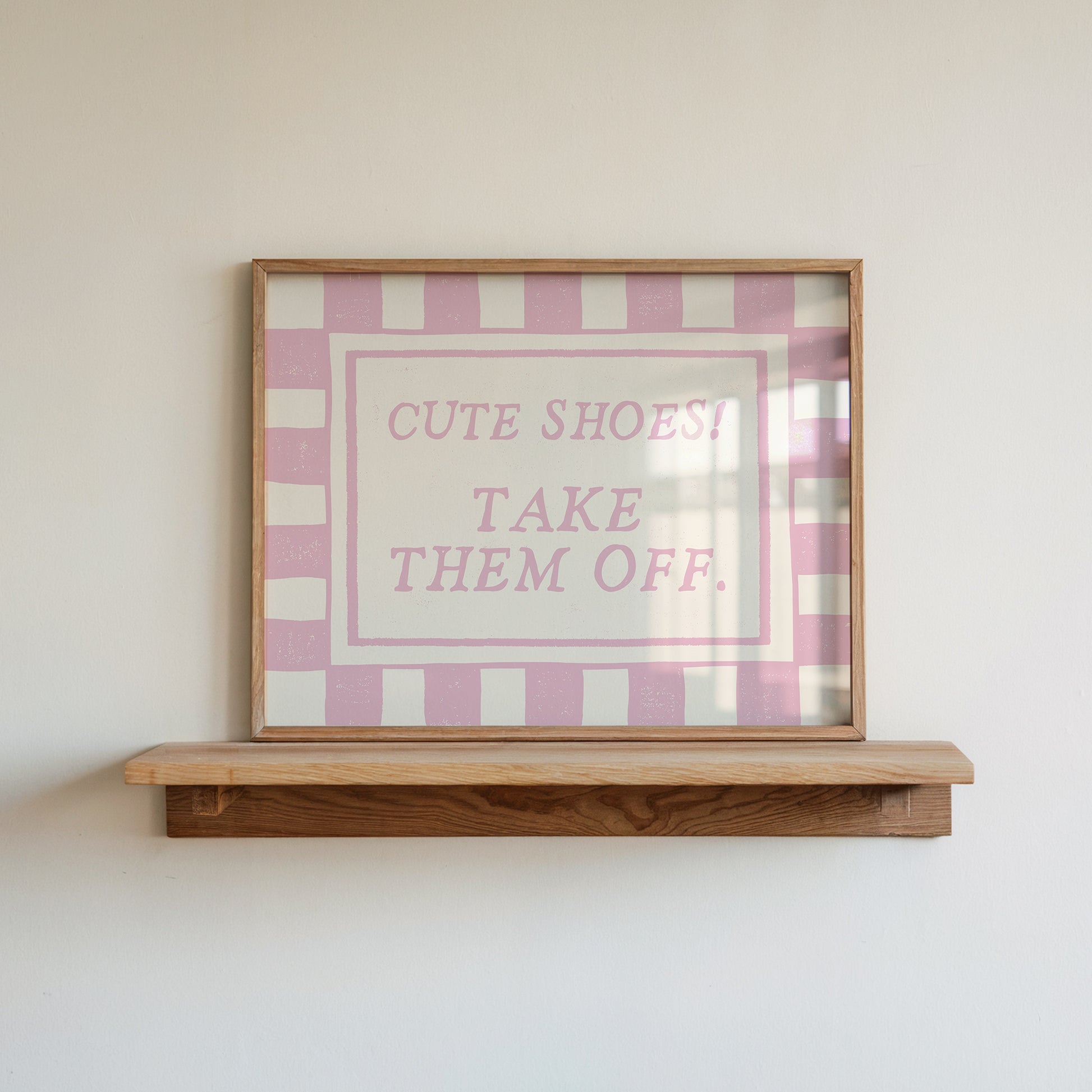Horizontal wall print with pink and cream checkered border and a cream centre text box in bold serif typography reading Cute Shoes! Take Them Off. in dusty pink